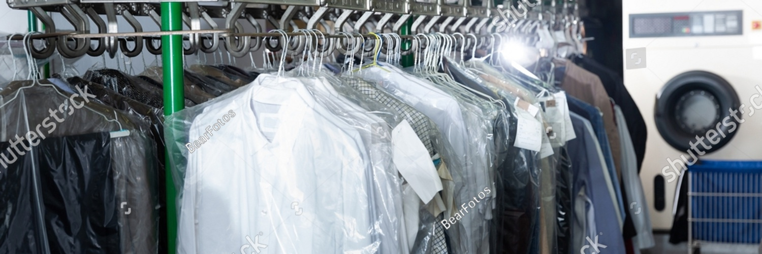 stock photo clean clothes packed in plastic bags hanging on racks after cleaning at dry cleaning facility 2131967377