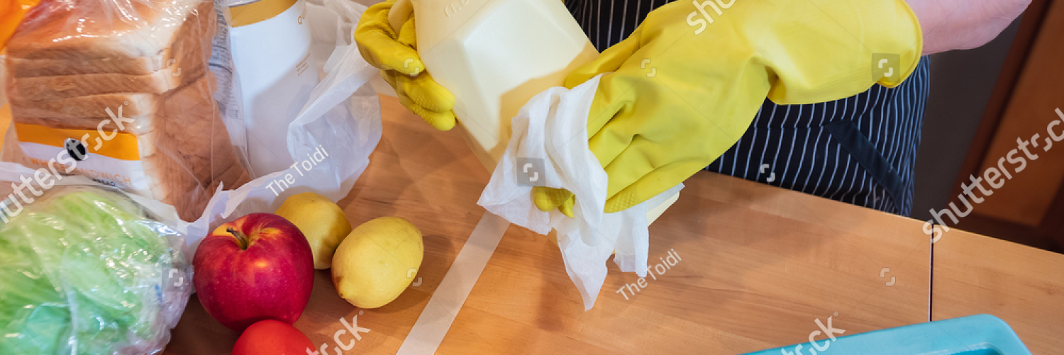 stock photo coronavirus pandemic wiping food packages after shopping for groceries woman wearing gloves and 1695742912
