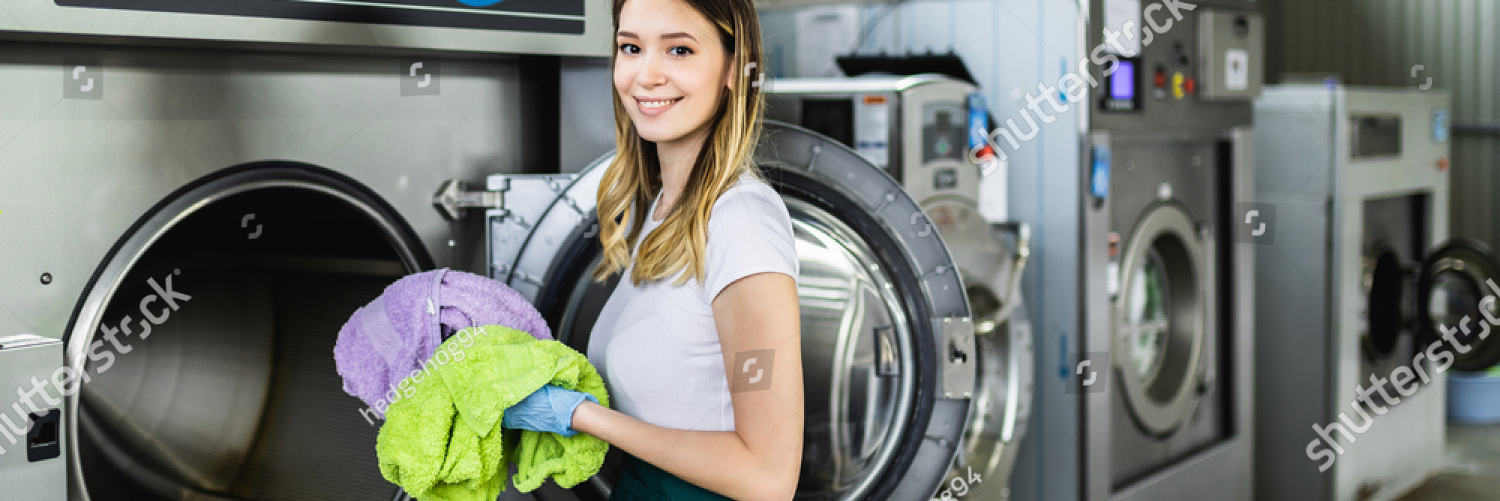 stock photo female worker loads the laundry clothing into the washing machine at the dry cleaners 1928786012