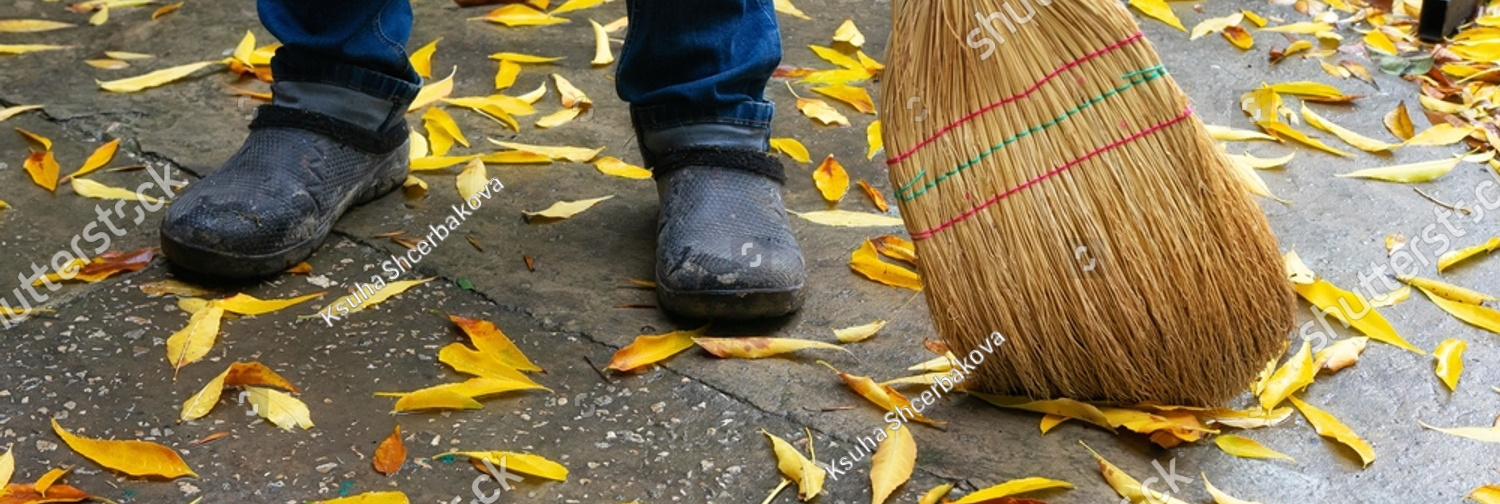 stock photo man sweeping a broom yard on the street from yellow leaves 2056174991