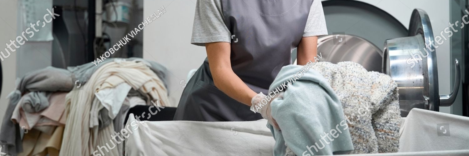 stock photo worker of laundry shop loading industrial washing machine with clothes 2325542999